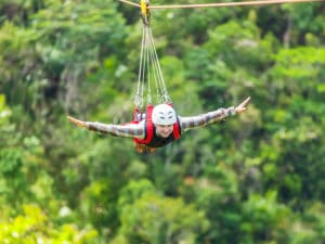 Men enjoying zip-line flying over the forest at Gunstock Mountain