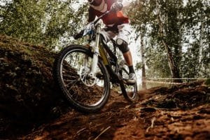 rider of bike downhill mountain biking trail in sunlight